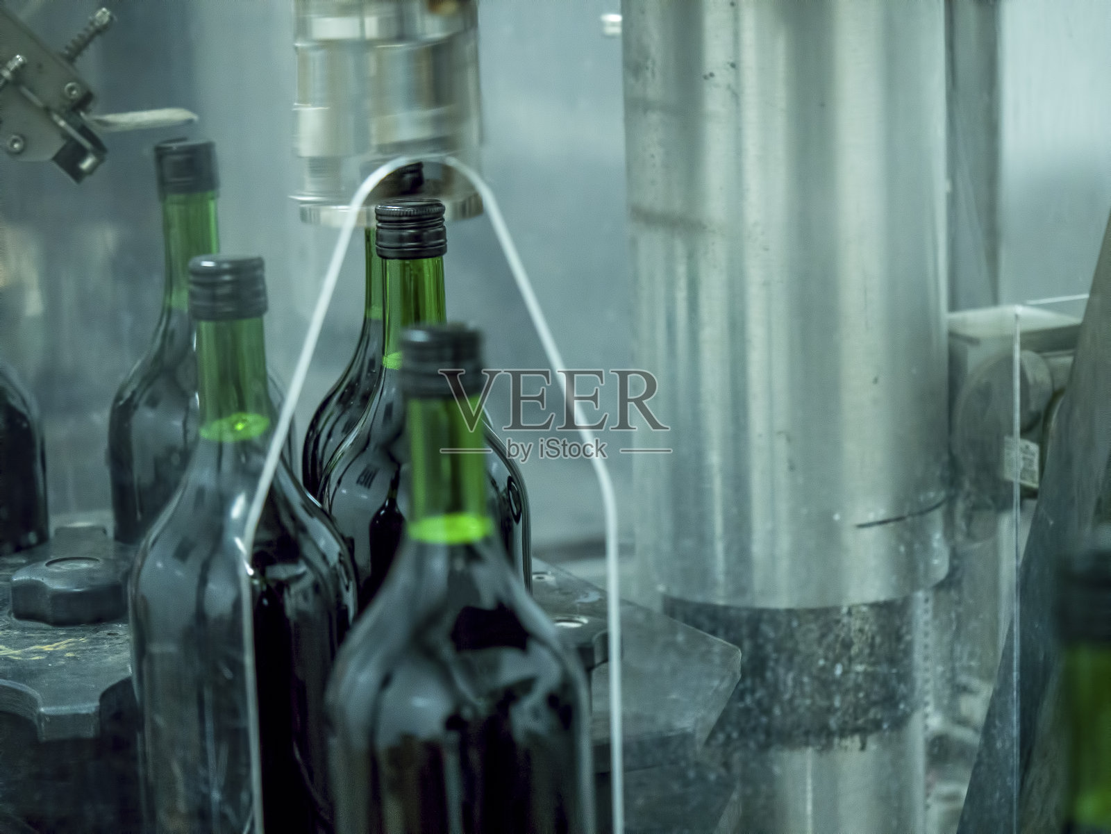 工厂生产线上的葡萄酒灌装和瓶盖照片摄影